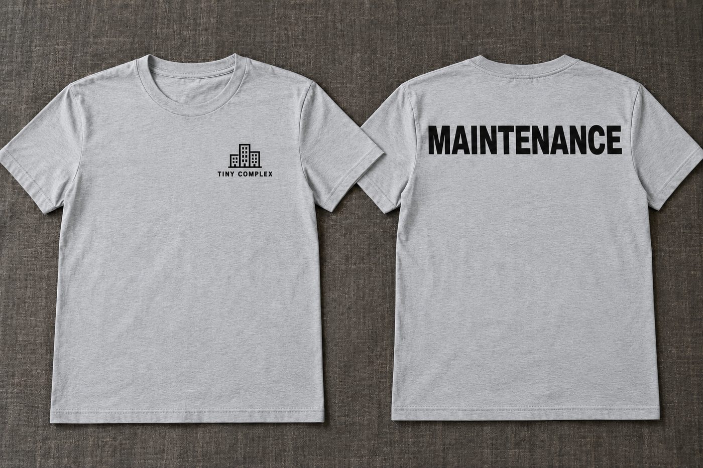 Two light grey t-shirts side by side. The front shows a building icon and the name TINY COMPLEX on the chest. The back shows MAINTENANCE in large black capitals.