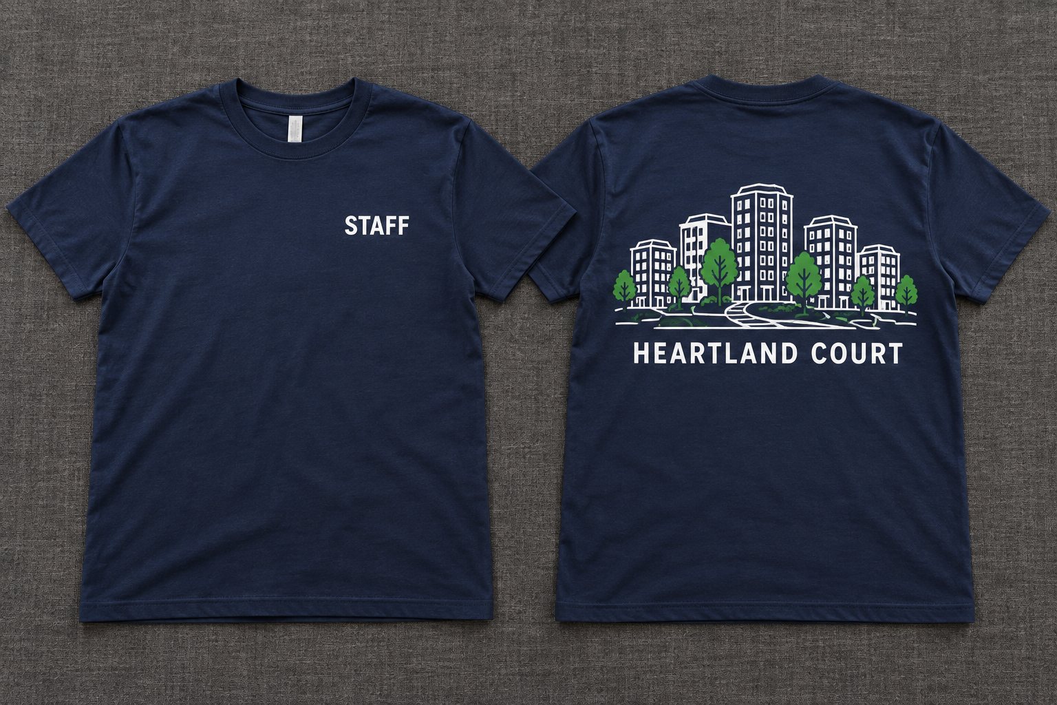 Two navy t-shirts side by side. The front shows STAFF printed small on the chest. The back shows a white line drawing of five apartment buildings with green trees and a pathway above the name HEARTLAND COURT.